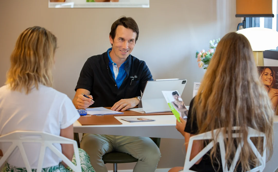 Le Dr Charles Bellec échange au bureau avec deux personnes en consultation